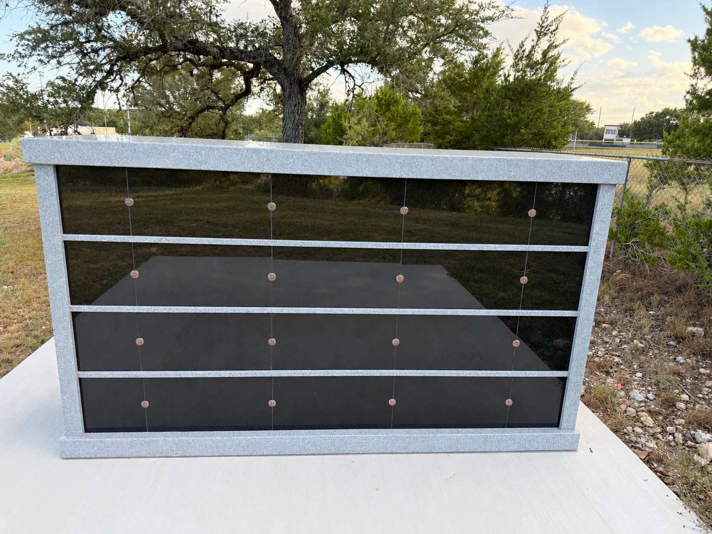The installed columbarium with polished black niche covers and a silver-gray granite frame.