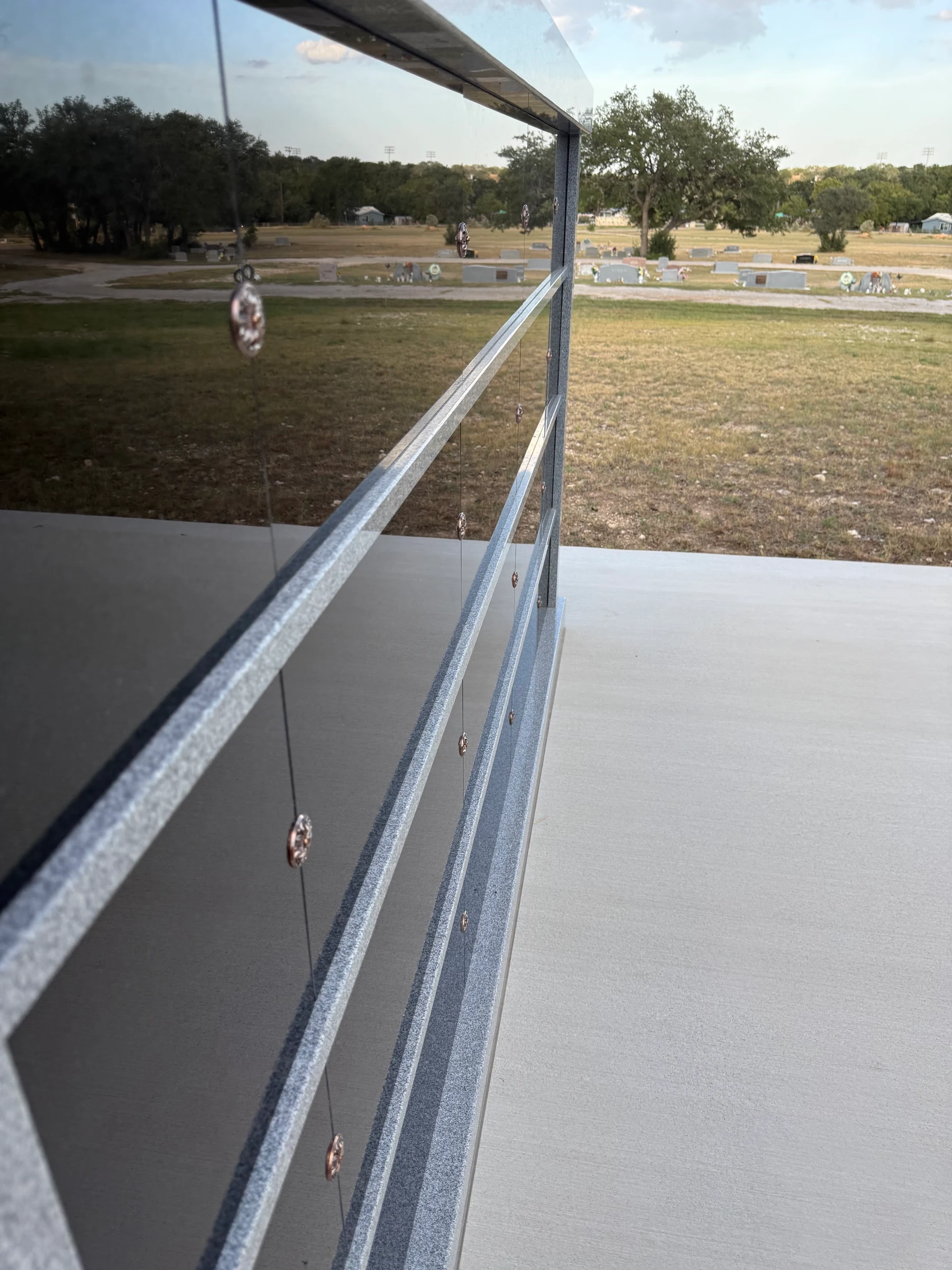 Trees and cemetery grounds reflected in the columbarium’s polished granite.